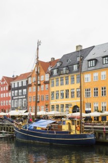 Colourful 17th century apartment buildings and houses with moored blue and yellow sailboat along