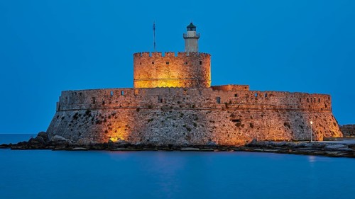 Ancient castle walls with a lighthouse in the blue hour in a quiet atmosphere, night shot, Fort of