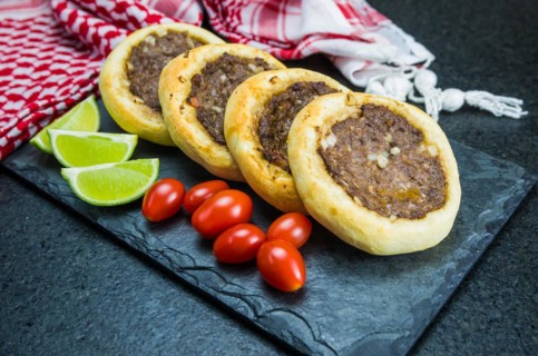 Delicious Lebanese (Arabic) food, genuine sfihas on a slate plate with tomatoes and lemons in the