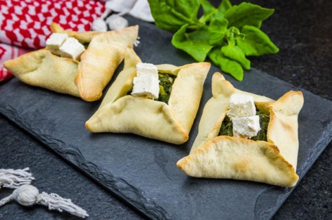 Delicious Lebanese (Arabic) food, spinach sfiha with ricotta cheese on a black slate stone