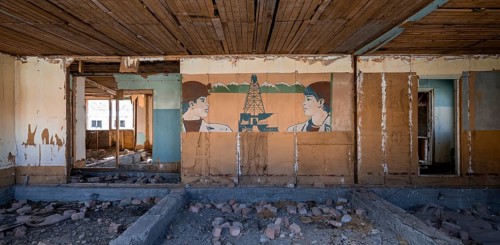 Destroyed abandoned classroom of the old school, wall painting with Soviet miners, ghost town,