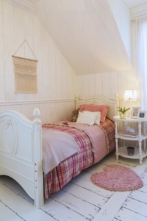 Single bed with red, pink and grey tartan bedspread, white painted antique style wooden headboard