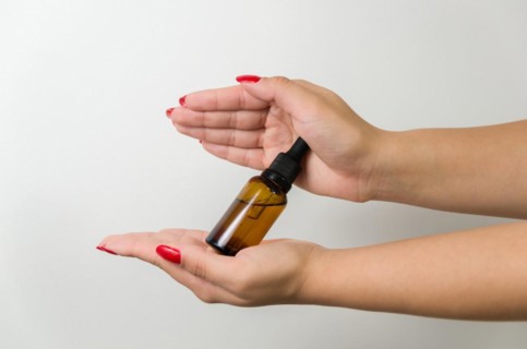 Product package with serum and a woman hand in studio on a background to promote an antiaging