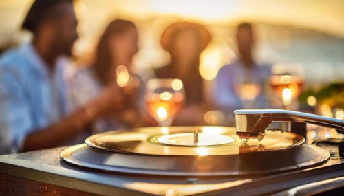 Friends enjoy drinks vinyl record playing together in cozy setting at sunset, bokeh effect ai
