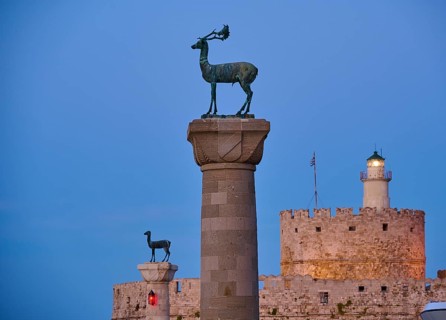 Deer statue on a pillar in front of a fortress wall and a lighthouse at dusk, Deer statue, Deer