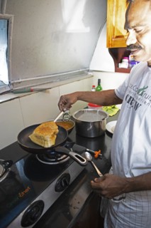 Indian man frying a dosa or pancake in a ship's galley, traditional Kerala dish, Kerala, India,