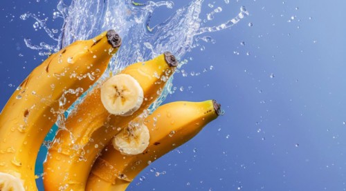 A bunch of yellow fresh bananas immersed in water and produce splash, AI generated