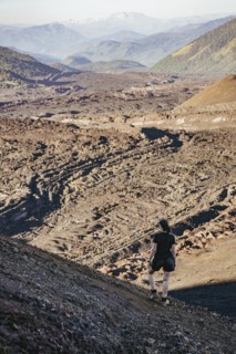 Young woman looking at lava fields, Crater Navidad, Lonquimay volcano, Malalcahuello National