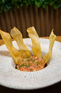 PERUVIAN FOOD. Spiced Salmon Ceviche with Chives and Lime on a white plate served with Fried Sweet