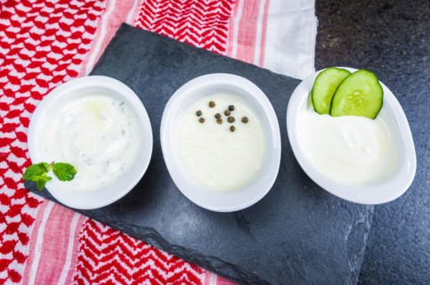 Delicious Lebanese (Arabic) food, thum, labneh and tzatziki sauces on black slate stone background