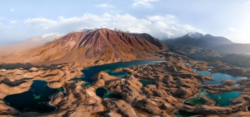 Atmospheric aerial view, high mountain landscape with glacier moraines and mountain lakes, behind