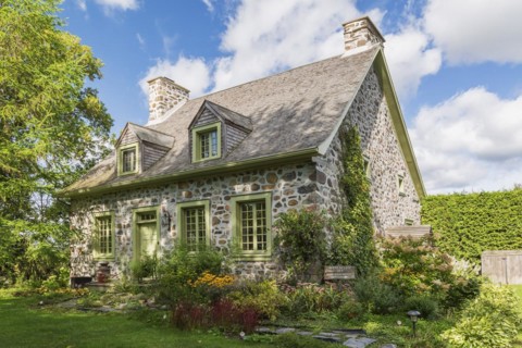 Old circa 1735 Canadiana fieldstone house facade with lime green trim and cedar wood shingles roof