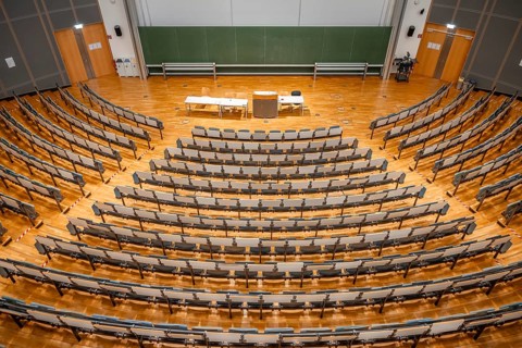 View from above into an empty lecture theatre with rows of seats and lectern, interior photo,