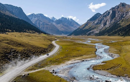 Car on road, mountain river in green mountain valley in the Tien Shan Mountains, Jety Oguz,