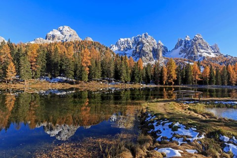 An idyllic lake reflects snow-covered mountains and autumnal trees, Italy, South Tyrol, Belluno,