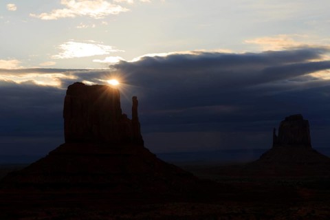 The last light of the sun shines from behind a rock needle and creates a mystical atmosphere,
