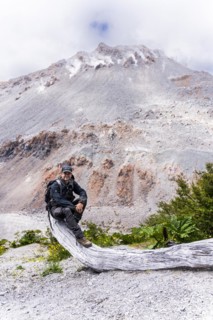 Young man sits in front of a volcano, Chaiten Volcano, Carretara Austral, Chile, South America
