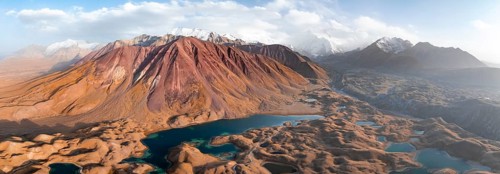 Atmospheric aerial view, high mountain landscape with glacier moraines and mountain lakes, behind
