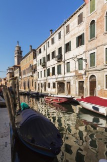 Narrow canal with moored boats and Renaissance architectural style residential palace buildings,