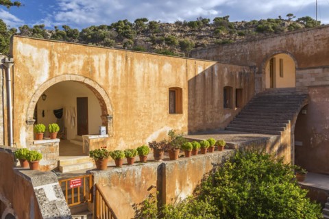 Stone staircase leading to cloister and wall with various plants in terracotta planters in inner