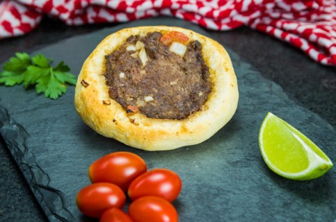 Delicious Lebanese (Arabic) food, legitimate sfihas on a black granite background with tomatoes,