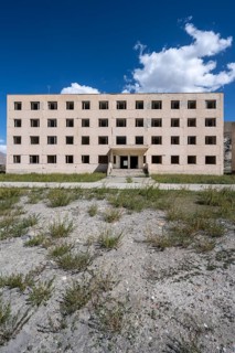 Abandoned destroyed residential building, old Soviet block of flats in the ghost town, Engilchek,