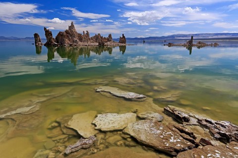 Limestone tufa structures protrude into a lake with clear water and a cloudy sky, Mono Lake, North