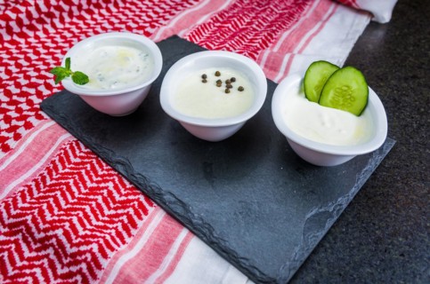 Delicious Lebanese (Arabic) food, thum, labneh and tzatziki sauces on black slate stone background