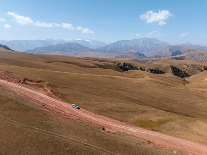 Moldo-Ashuu Pass, car on road between yellow hills, near Baetov, Naryn region, Kyrgyzstan, Asia
