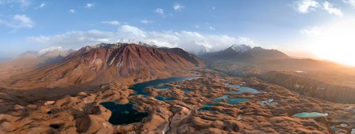 Atmospheric aerial view, high mountain landscape with glacier moraines and mountain lakes, behind