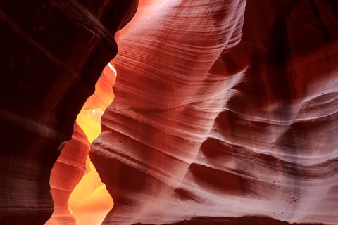 Warm rays of sunlight illuminate the undulating structures inside a rock cave, Upper Antelope