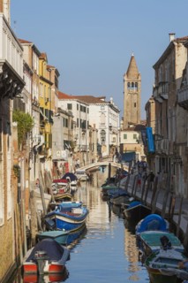 Moored boats on San Barnaba canal with footbridge and old architectural style residential buildings