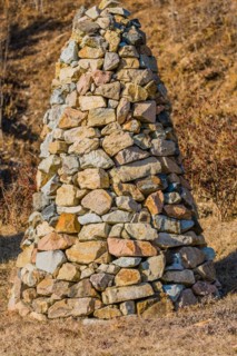 Closeup of pile of stones in the shape of an upside down cone in a public road side park near