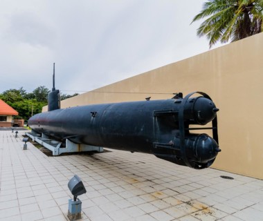 Japanese made two man submarine with view of torpedo tubes on public display in front of a concrete