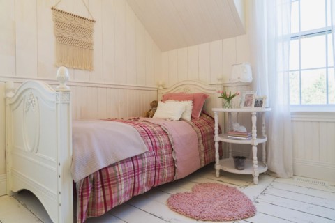 Single bed with red, pink and grey tartan bedspread, white painted antique style wooden headboard