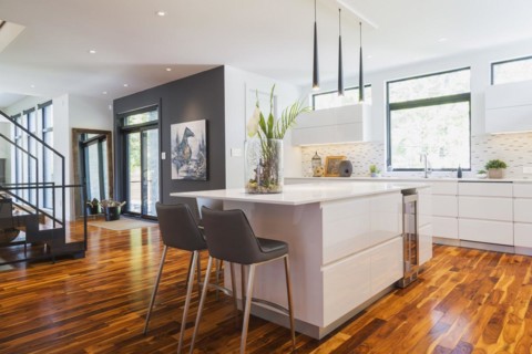 White high-gloss lacquered cabinets and island with grey leather bar stools and white quartz