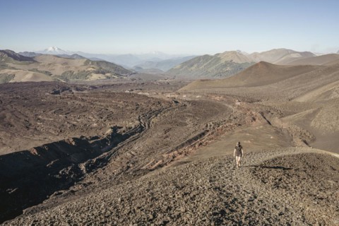 Young woman walking through lava fields, Crater Navidad, Lonquimay volcano, Malalcahuello National