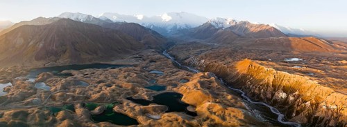 Atmospheric aerial view, high mountain landscape with glacier moraines and mountain lakes, behind