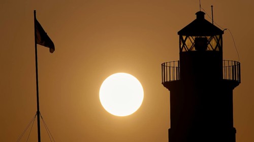 Silhouette of a lighthouse in front of an Orange coloured sky at sunrise, sunrise, dawn, Fort of