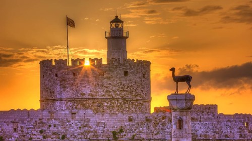 Lighthouse on a castle, pierced by the rays of the rising sun, sunrise, dawn, European roe deer