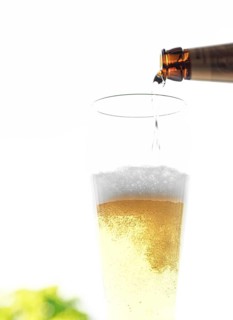 Beer is poured from a bottle into a glass, bubbles and foam are visible