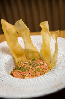 PERUVIAN FOOD. Spiced Salmon Ceviche with Chives and Lime on a white plate served with Fried Sweet