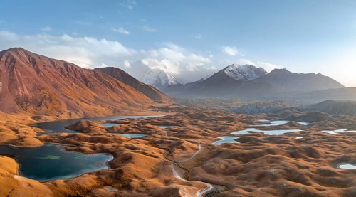 Atmospheric aerial view, high mountain landscape with glacier moraines and mountain lakes, behind