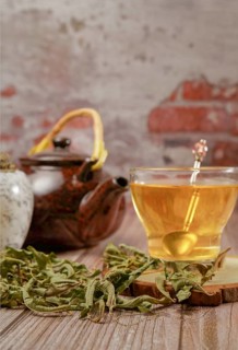 Lemon verbena infusion in a glass cup with a marble mortar and pestle and a ceramic teapot with
