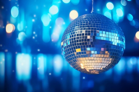 A disco ball is suspended from the ceiling at party in nightclub, reflecting the lights and