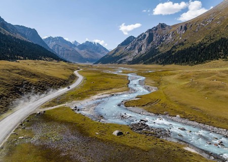 Car on road, mountain river in green mountain valley in the Tien Shan Mountains, Jety Oguz,