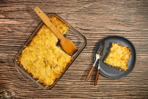 Top view of pie with meat and potato baked in oven in glass baking tray and on a plate