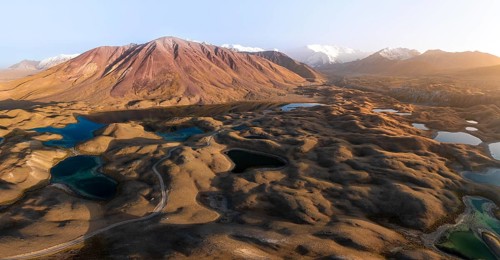 Atmospheric aerial view, high mountain landscape with glacier moraines and mountain lakes, behind