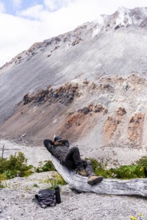 Young man relaxes in front of a volcano, Chaiten Volcano, Carretara Austral, Chile, South America