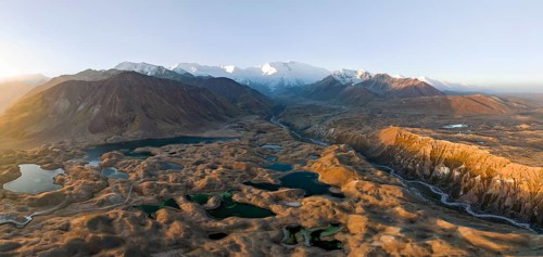 Atmospheric aerial view, high mountain landscape with glacier moraines and mountain lakes, behind